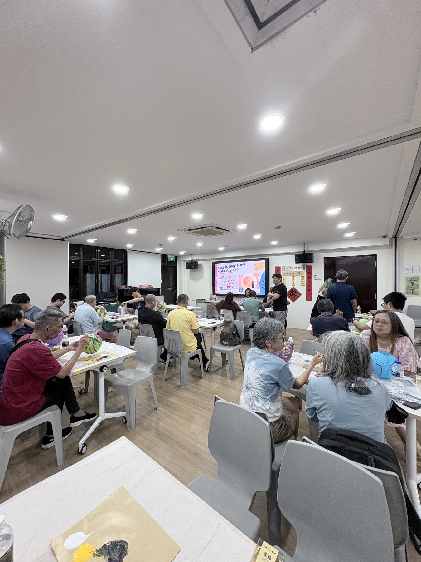 Older adults painting colourful paper lanterns together in a community workshop