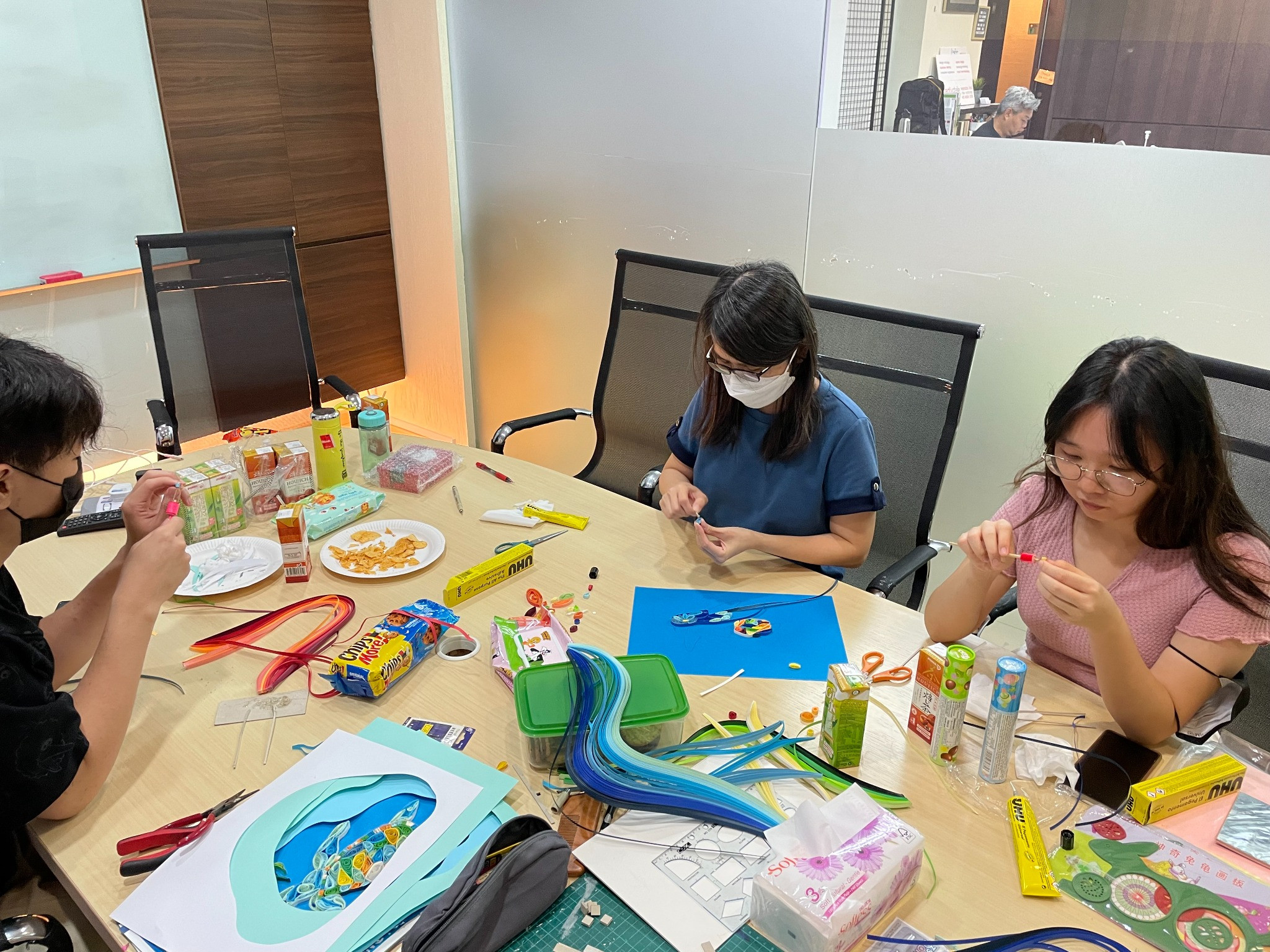 Participants creating paper quilling artworks around a shared table