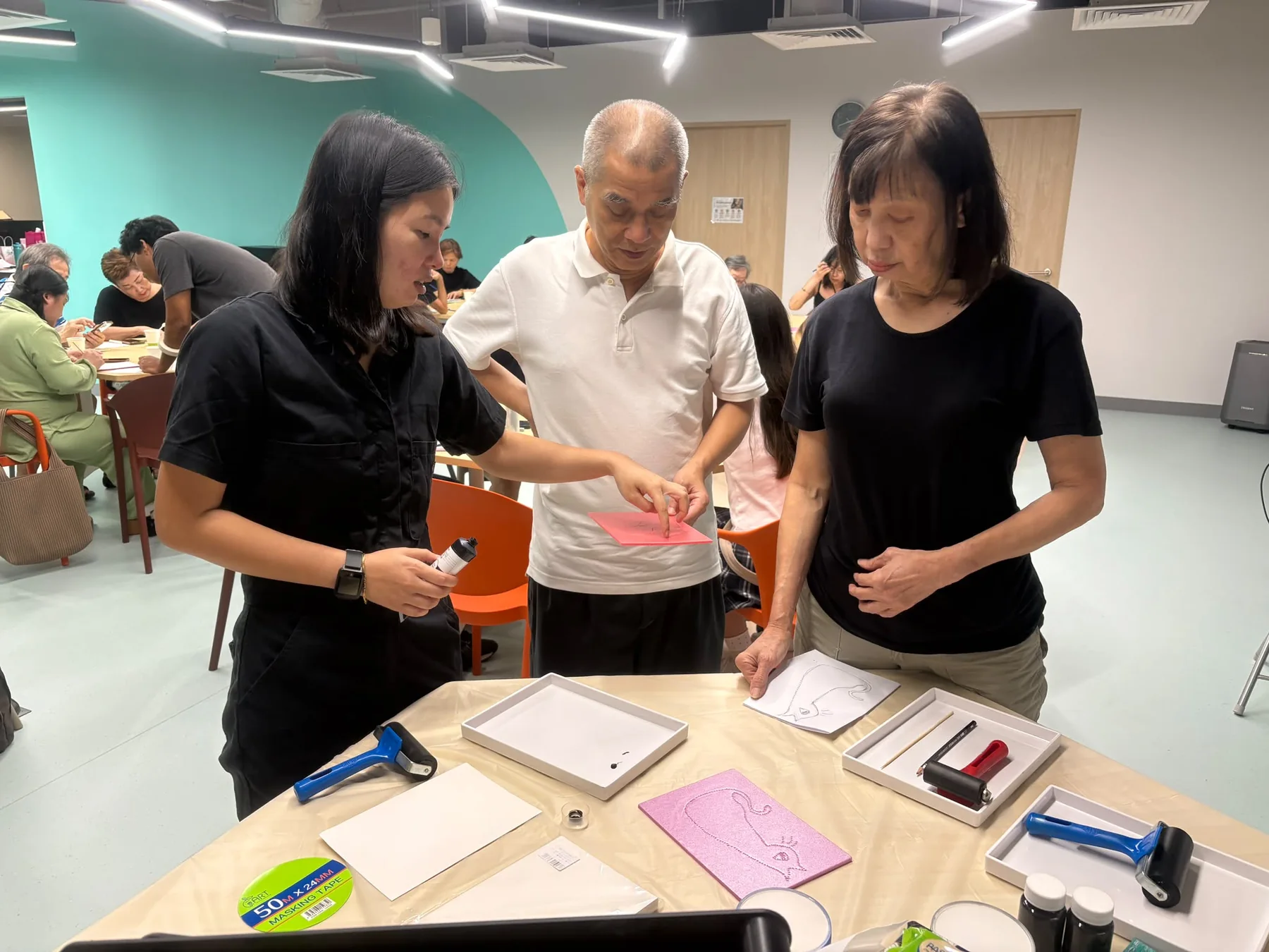 A facilitator guiding participants through a printmaking process at a workshop table